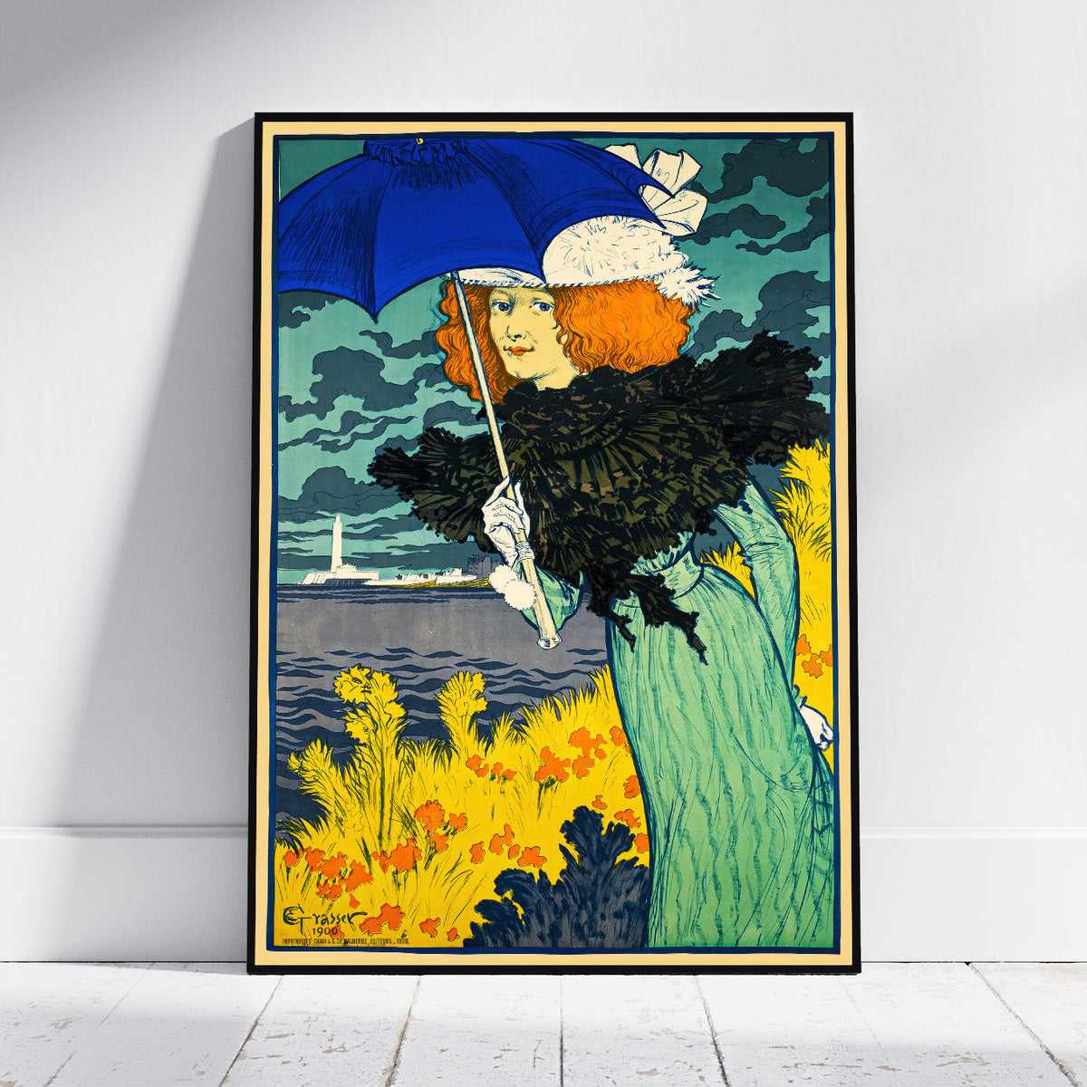 A framed vintage-style art print leaning against a white wall on a light wood floor. The artwork shows a woman in a teal dress holding a dark blue umbrella, with yellow flowers, dark clouds, and a distant lighthouse.