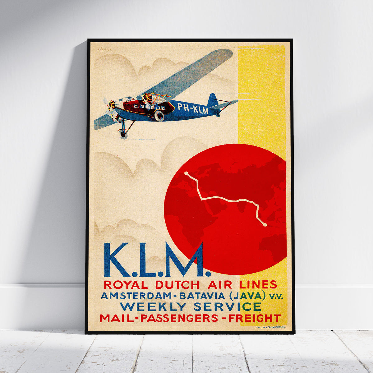 A framed vintage-style travel poster for KLM Royal Dutch Air Lines leaning against a white wall on a light floor. The poster shows a blue biplane flying above a large red sun on a cream background, with bold KLM lettering and service text at the bottom.