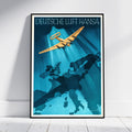 A framed vintage-style travel poster leaning against a white wall on a light floor. The poster reads 'DEUTSCHE LUFT HANSA' at the top and features a yellow airplane flying over a blue map silhouette of Germany and surrounding countries.