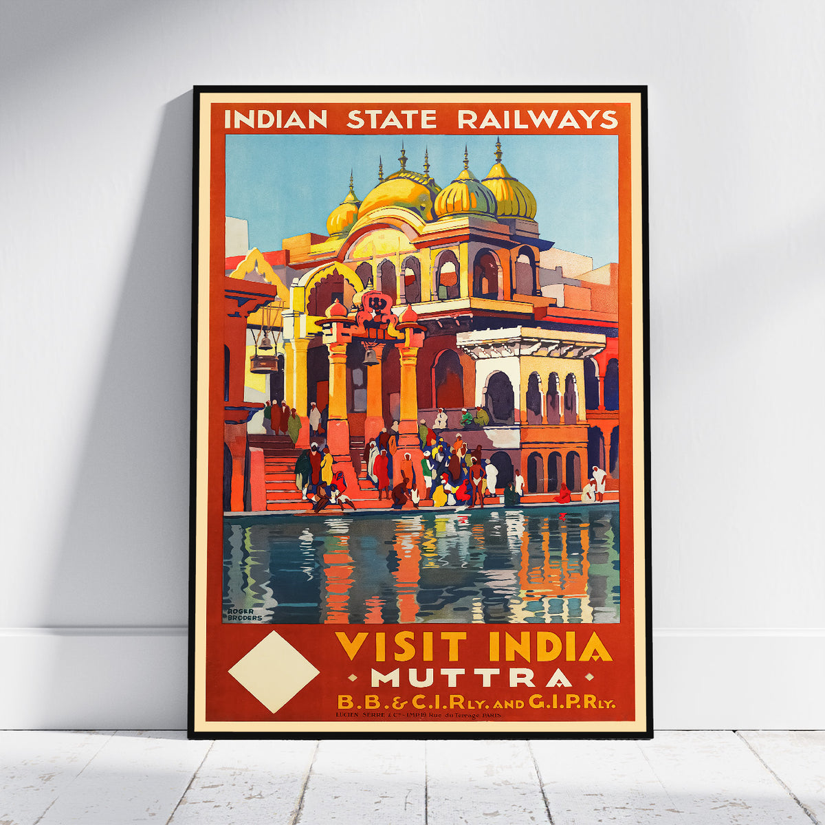 A vintage-style travel poster for Indian State Railways, featuring a colorful illustration of a domed palace and people by Muttra, India. The poster is displayed leaning against a white wall on a light wooden floor.