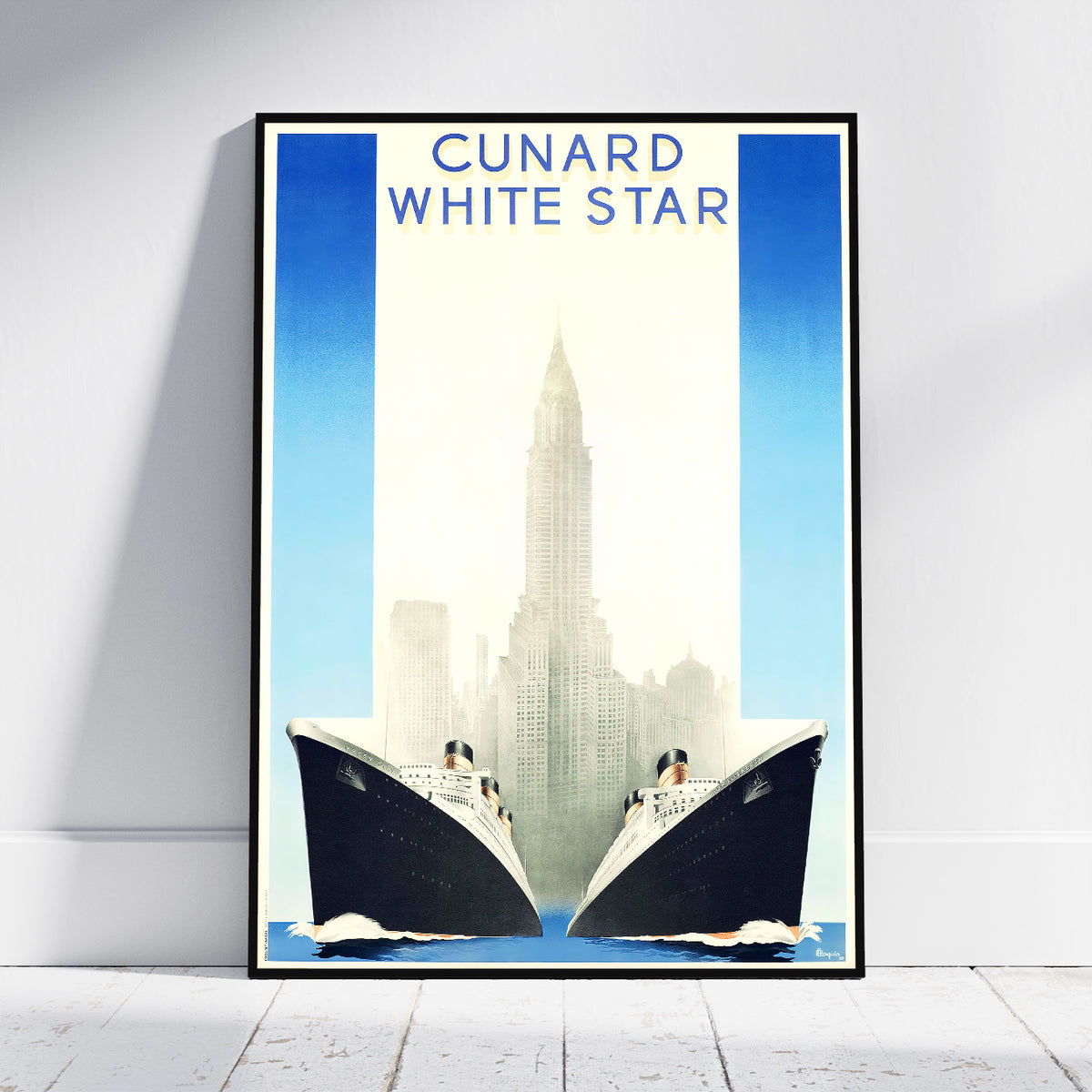 A framed vintage-style travel poster leaning against a white wall on a light wood floor. The poster reads 'CUNARD WHITE STAR' at the top and depicts two large ocean liners facing each other in front of a city skyline with a tall central tower.