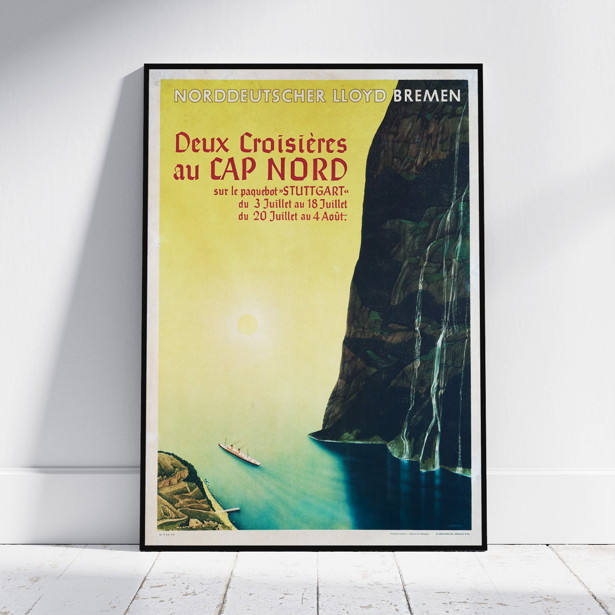 A framed vintage travel poster for Lloyd Bremen's 'Deux Croisières au Cap Nord' ship journey, leaning against a white wall on a light wood floor.