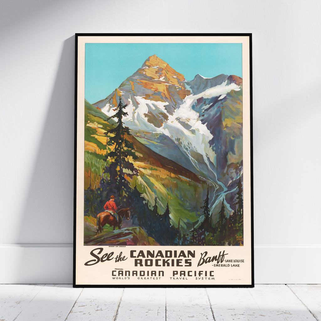 A framed vintage-style travel poster leaning against a white wall on a light floor. The artwork shows a mountain landscape with snow, green and brown slopes, trees, and a small rider in the lower left.