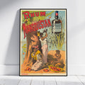 A framed vintage advertising poster for 'Rhum Manguistan' leaning against a white wall on a light wood floor. The poster features a colorful illustration with a large bottle, workers, fruit, and sugarcane, with the brand name 'MANGUISTAN' visible on the bottle graphic.