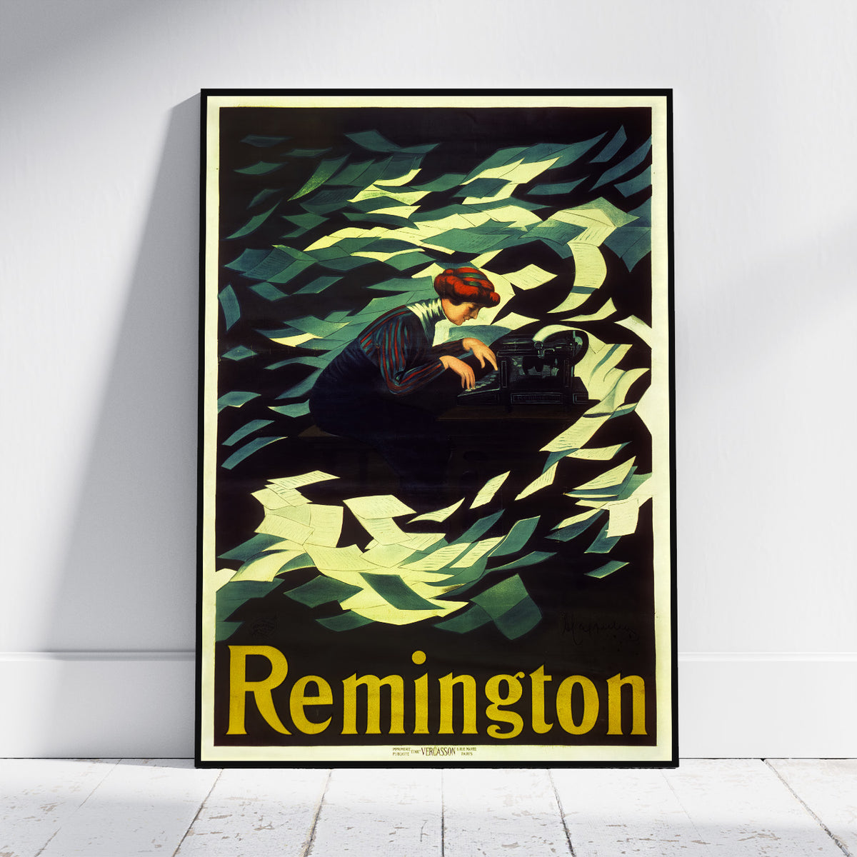 A framed vintage Remington poster leaning against a white wall on a light wood floor. The poster features an illustration of a person working at a typewriter surrounded by green and black leaf-like shapes, with the brand name 'Remington' in large yellow letters at the bottom.