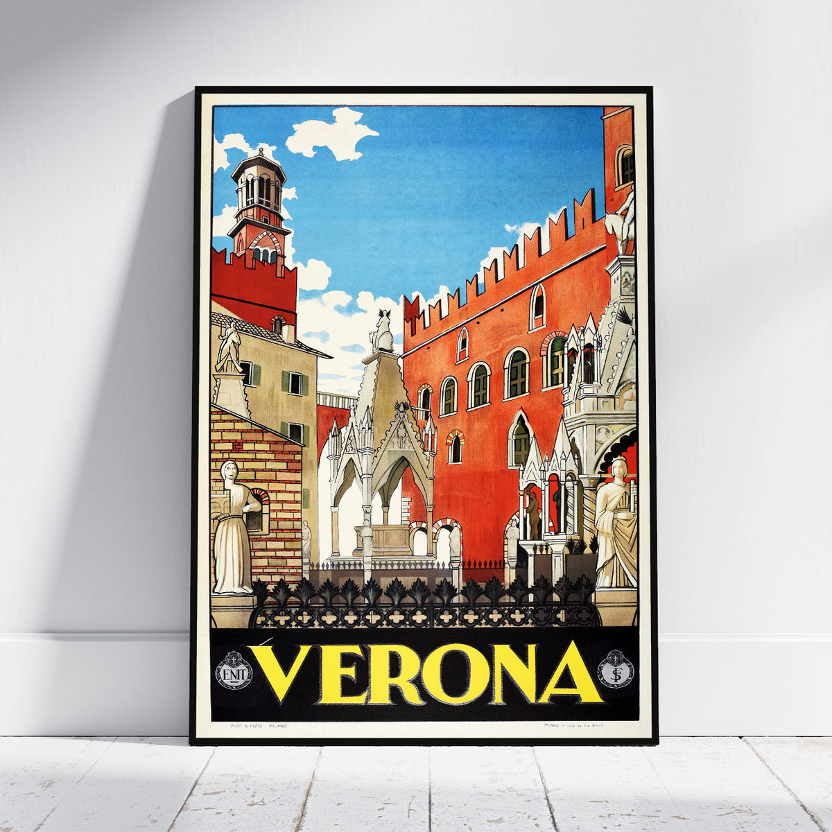 A framed vintage-style travel poster of Verona, Italy, leaning against a white wall on a light wood floor. The poster features a colorful illustration of the city's architecture, including a prominent red-orange building, a bell tower, and a blue sky, with 'VERONA' printed in bold yellow letters at the bottom.