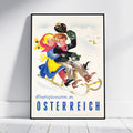 A framed vintage-style travel poster leaning against a white wall on a light wood floor. The poster shows two children sledding in a snowy mountain landscape with the text 'Winterfreuden in OSTERREICH' in blue at the bottom.
