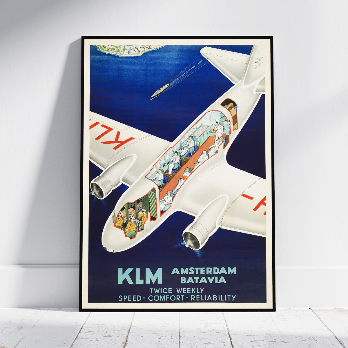 A framed vintage-style KLM travel poster leaning against a white wall on a light floor. The poster shows a cutaway view of a white airplane flying over deep blue water, with passengers visible inside and text reading 'KLM Amsterdam Batavia' and 'Twice Weekly Speed - Comfort - Reliability'.