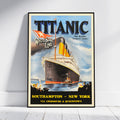 A framed vintage-style Titanic travel poster leaning against a white wall on a light wood floor. The poster shows the Titanic sailing at sea with large 'TITANIC' text at the top, 'Walters Star Line' branding, and destination text reading 'Southampton ~ New York'.