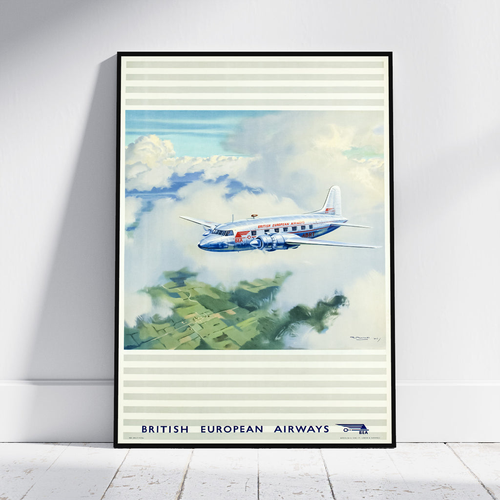 A framed vintage-style poster leaning against a white wall on a light wood floor. The artwork shows a blue, white, and red British European Airways airplane flying through clouds above green fields.