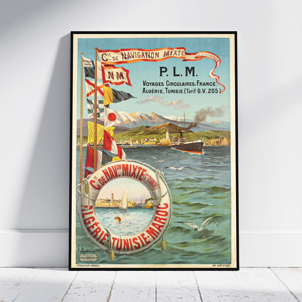 A framed vintage travel poster leaning against a white wall on a light wood floor. The poster features a colorful illustration of a ship at sea with mountains in the background, a life preserver in the foreground, and French text including 'C.