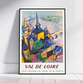 A framed vintage-style travel poster leaning against a white wall on a light wood floor. The poster depicts an abstract cityscape with spires and buildings in blue, yellow, green, and purple, with the text 'VAL DE LOIRE' and 'SOCIETE NATIONALE DES CHEMINS DE FER FRANCAIS' at the bottom.