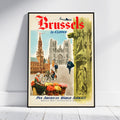 A framed vintage-style travel poster for Brussels, leaning against a white wall on a light floor. The poster features large red 'Brussels' lettering, illustrated architecture, people, flowers, and 'Pan American World Airways' text at the bottom.