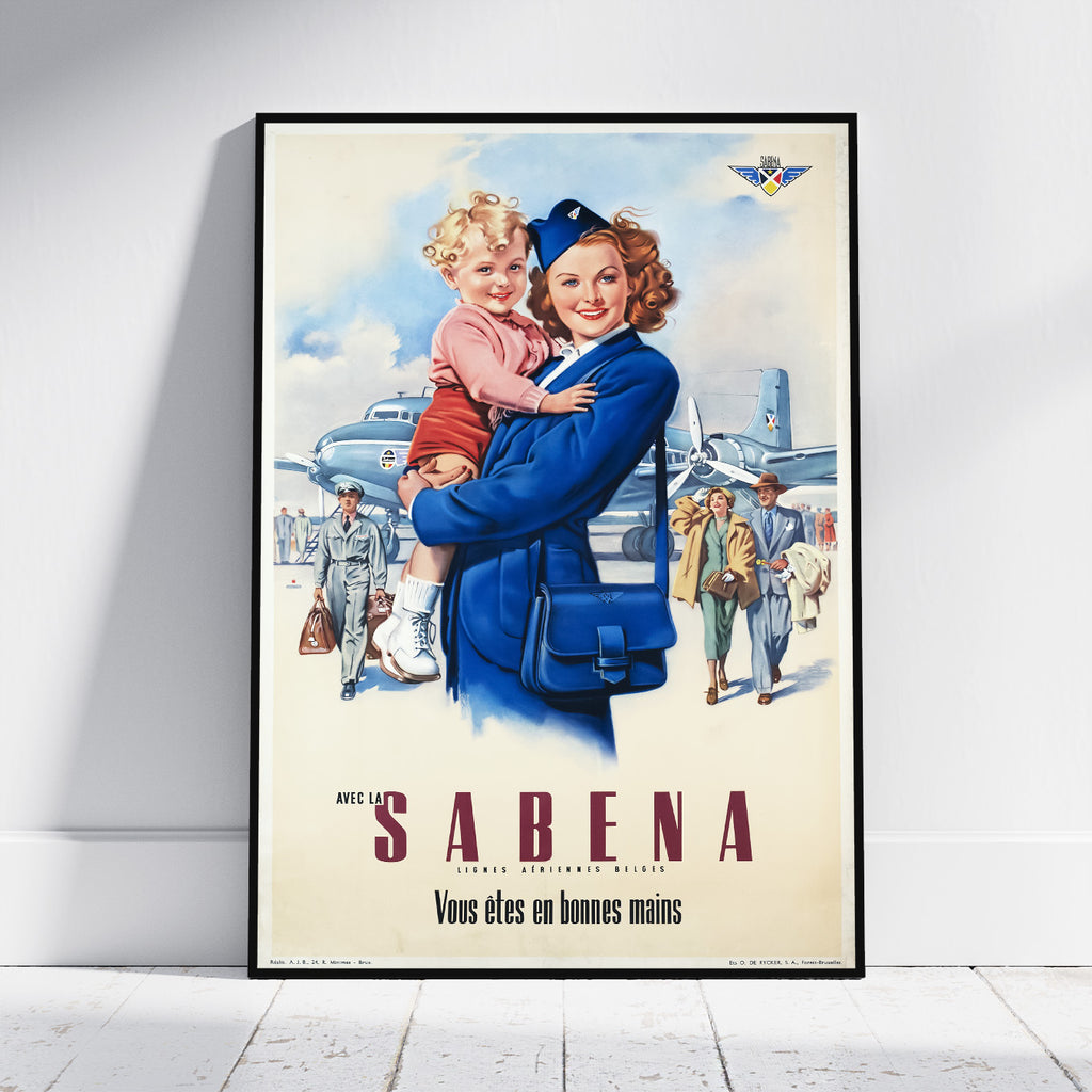 A framed vintage-style travel poster leaning against a white wall on a light wood floor. The poster shows a smiling woman in a blue uniform carrying a young child, with airplanes and travelers in the background and the text 'AVEC LA SABENA' and 'Vous etes en bonnes mains'.