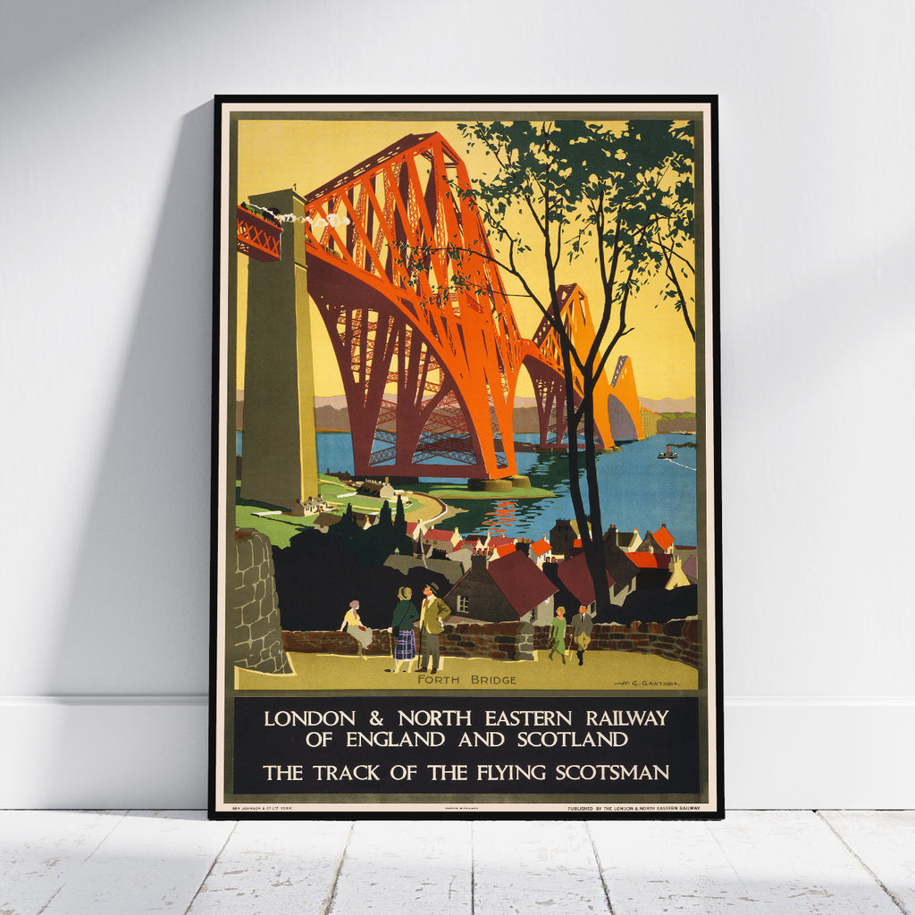 A framed vintage travel poster of the Scottish Borders Railway bridge over the River Tyne, leaning against a white wall on a light wood floor.