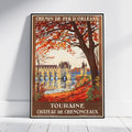A framed vintage-style travel poster leaning against a white wall on a light wood floor. The poster reads “CHEMIN DE FER D'ORLÉANS” at the top and “TOURAINE À CHÂTEAU DE CHENONCEAUX” at the bottom, showing an autumn scene with orange-red leaves, a large tree, and a yellow chateau by the water.