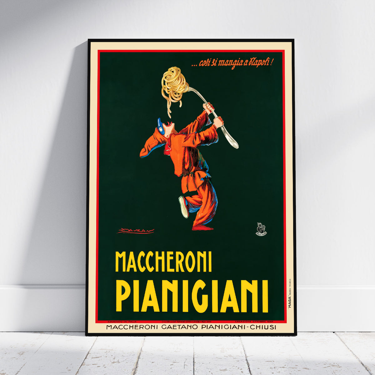A framed vintage-style poster leaning against a white wall on a light floor. The poster features an illustration of a person tossing spaghetti in the air, with the text '.
