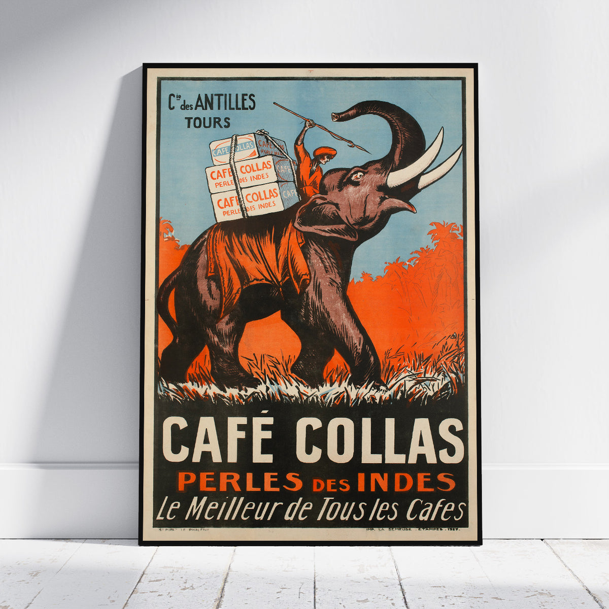 A vintage-style illustrated poster for Café Collas leaning against a white wall on a light wood floor. The artwork shows an elephant carrying boxes labeled Café Collas, with large text reading 'CAFÉ COLLAS' and 'PÉRLES DES INDES' in orange, cream, black, and blue tones.