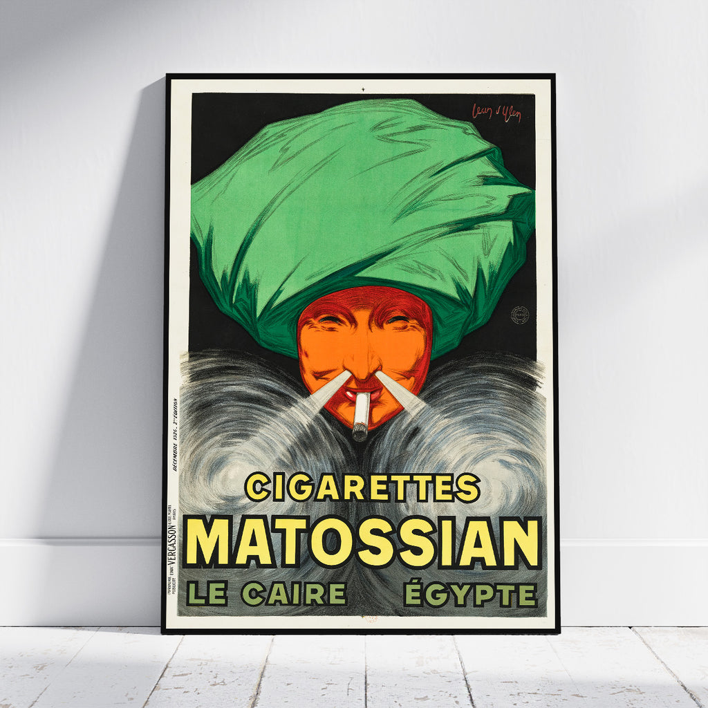 A framed vintage-style poster leaning against a white wall on a light floor. The poster shows a person wearing a large green turban and smoking, with bold yellow text reading 'CIGARETTES MATOSSIAN LE CAIRE ÉGYPTE'.