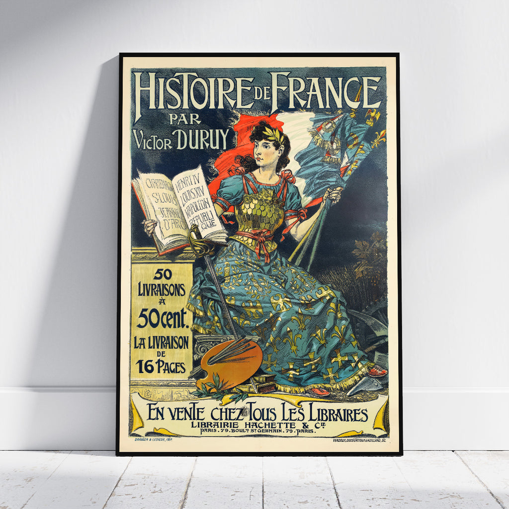 A framed vintage French book cover poster titled 'Histoire de France' by Victor Duruy, leaning against a white wall on a light wood floor. The poster features an illustrated seated woman in ornate blue and gold clothing with a red hat, holding a book and a flag, with decorative text and a yellow publisher box.