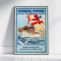 A framed vintage-style travel poster leaning against a white wall on a light wood floor. The poster features a white passenger ship on blue ocean waves with red and blue flags, and the text 'JADRANSKA PLOVIDBA SUŠAK' at the top.