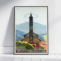 A framed vintage-style travel poster leaning against a white wall on a light wood floor. The artwork shows a church tower in a mountain village with the text 'FERROVIA ELETTRICA LVGANO - TESSERETE' and a circular logo at the top left.