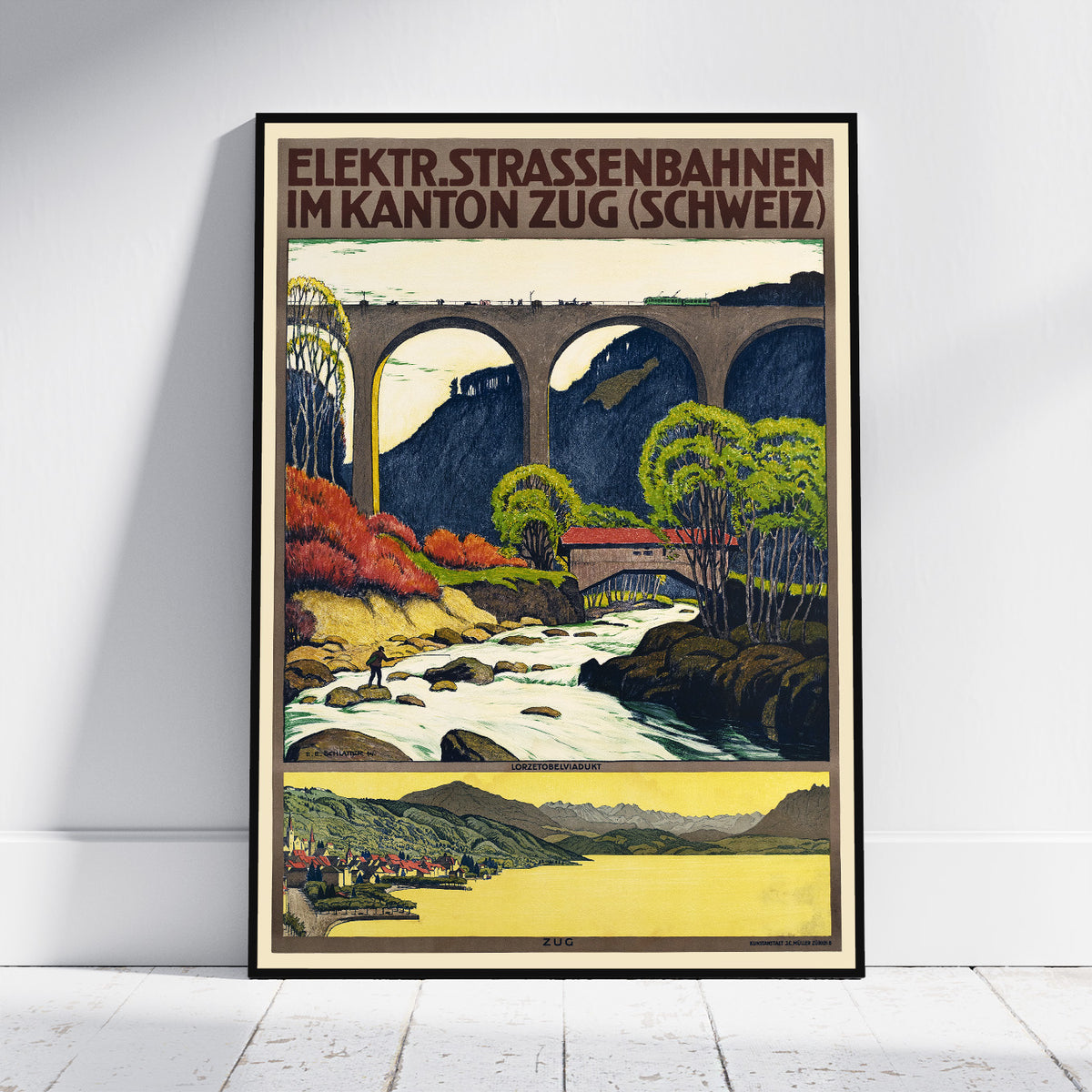 A framed vintage-style travel poster leaning against a white wall on a light floor. The poster shows an illustrated mountain railway scene with arches, trees, a river, and bold text at the top reading 'ELEKTR.