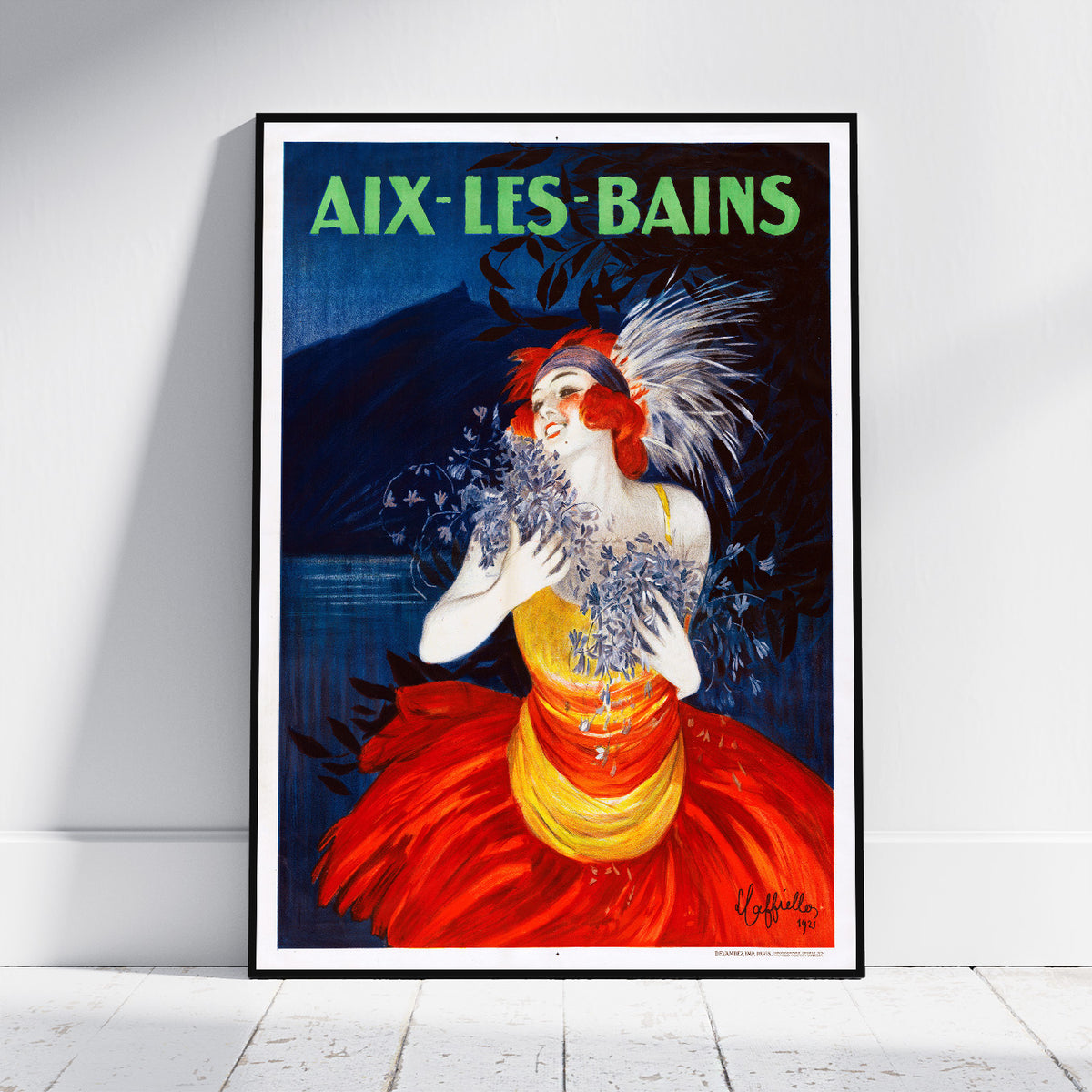 A framed vintage-style poster leaning against a white wall on a light floor. The poster shows a woman in a red and yellow dress with blue flowers, with the text 'AIX-LES-BAINS' at the top.