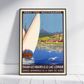 A framed vintage travel poster leaning against a white wall on a light floor. The poster features a sailboat on blue water with mountains and a town in the background, and text reading 'PARIS - LYON - MÉDITERRANÉE' and 'ÉVIAN-LES-BAINS & LE LAC LÉMAN'.
