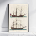 A framed vintage nautical print showing two antique sailing ships on an aged cream background, leaning against a white wall on a light wood floor.