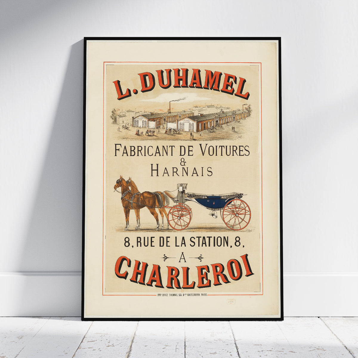 A framed vintage-style poster leaning against a white wall on a light floor. The poster features the text 'L.