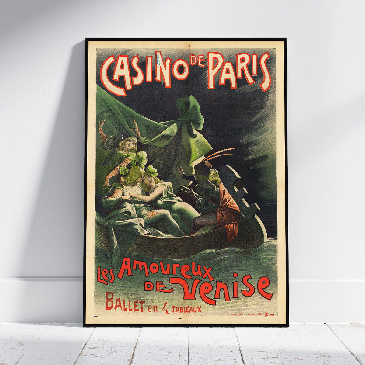 A framed vintage-style poster leaning against a white wall on a light floor. The poster reads "CASINO DE PARIS" and "Les Amoureux de Venise Ballet en 4 tableaux" with illustrated figures in a dark scene and red lettering.