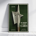 A framed vintage military poster leaning against a white wall on a light wood floor. The poster features a large silver battle axe on a dark green background with white text reading '26.
