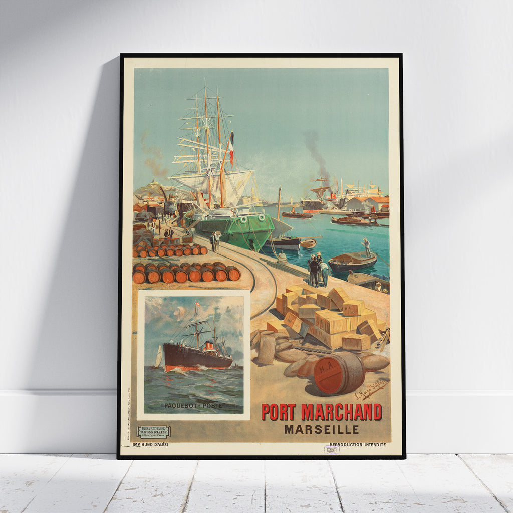 A framed vintage-style travel poster leaning against a white wall on a light floor. The poster depicts a Marseille harbor scene with ships, barrels, crates, and the text 'PORT MARCHAND MARSEILLE'.