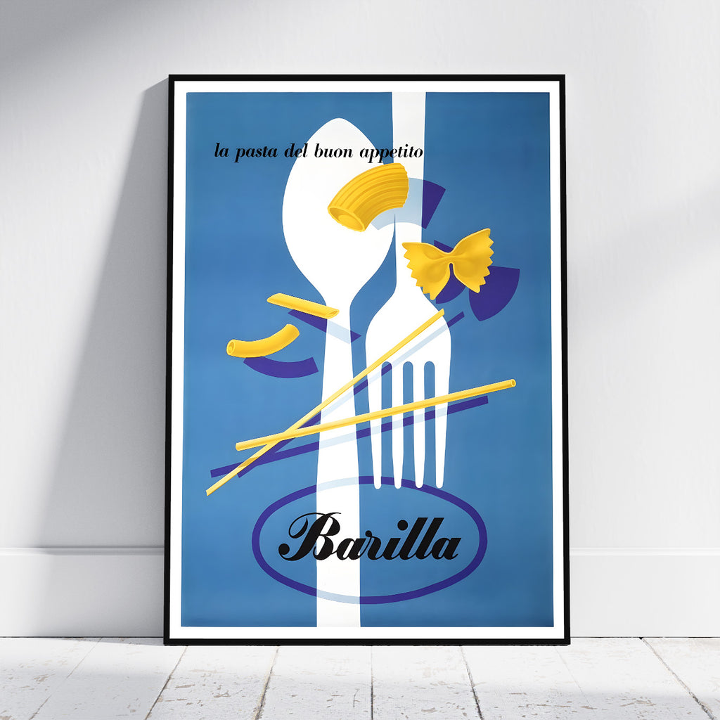 A framed art print featuring a retro-style blue and white illustration of a fork, spoon, pasta, and bow tie, with the text 'la pasta del buon appetito' and 'Barilla' at the bottom, leaning against a white wall on a light floor.