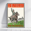 A framed vintage French military poster leaning against a white wall on a light wood floor. The poster features an illustration of a soldier on a galloping horse with the text 'FÉTE FÉDÉRALE DE S.