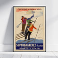 A framed vintage travel poster for French railways advertising 'Superbagnères - Luchon' ski resort, leaning against a white wall on a light wood floor. The poster features three skiers on a snowy slope with a cream background and bold blue and orange text.