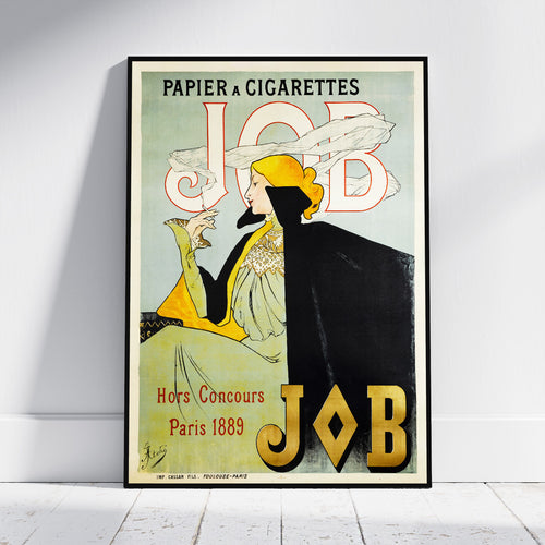 A framed vintage-style poster leaning against a white wall on a light floor. The poster features an Art Nouveau illustration with the text 'PAPIER A CIGARETTES JOB' and 'Hors Concours Paris 1889'.