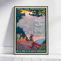 A vintage-style travel poster for the French Alps, leaning against a white wall on a light wood floor. The poster features a retro car with passengers, a map of the region, and text reading 'LA ROUTE DES ALPES' and 'PARIS - LYON - MÉDITERRANÉE'.