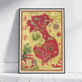 A framed vintage-style map poster of Indochina, leaning against a white wall on a light wood floor. The map features a warm beige background with red highlighted regions, green illustrations, and decorative cartographic details.