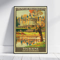 A framed vintage-style travel poster leaning against a white wall on a light wood floor. The poster shows a castle by a river with autumn trees and the text 'CHEMIN DE FER D'ORLÉANS' at the top and 'TOURAINE CIRCUITS AUTOMOBILES' at the bottom.