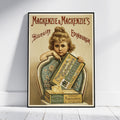 A framed vintage-style advertising poster leaning against a white wall on a light floor. The poster shows a young girl holding a box of MacKenzie & Mackenzie's Biscuits, with large decorative text reading 'Mackenzie & Mackenzie's Biscuits Edinburgh.