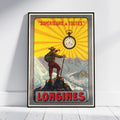 A framed vintage-style travel poster leaning against a white wall on a light floor. The poster features a mountain climber standing on a peak with a pocket watch above, yellow sunburst rays, and the text "SUPÉRIEURE A TOUTES" and "LONGINES.
