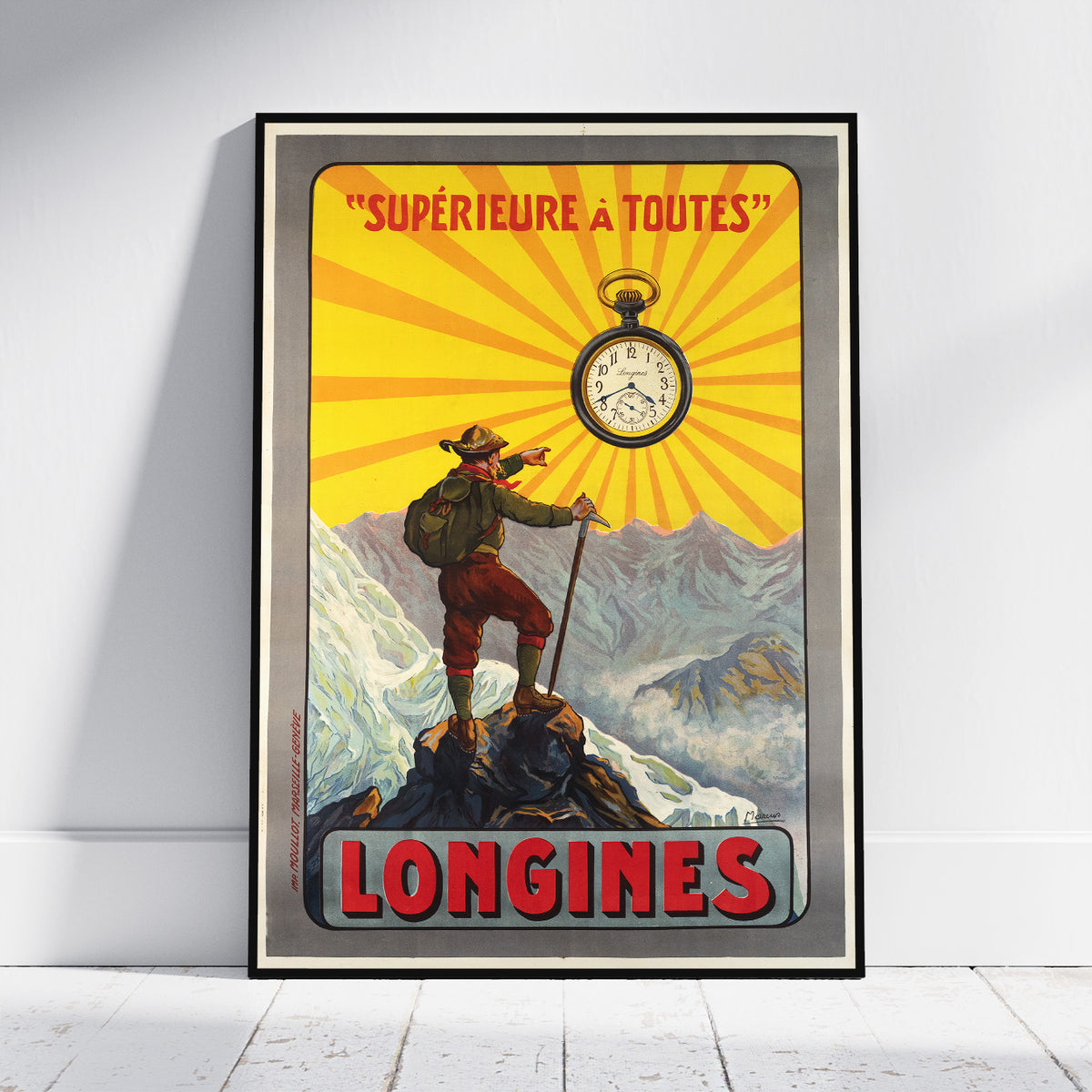 A framed vintage-style travel poster leaning against a white wall on a light floor. The poster features a mountain climber standing on a peak with a pocket watch above, yellow sunburst rays, and the text "SUPÉRIEURE A TOUTES" and "LONGINES.