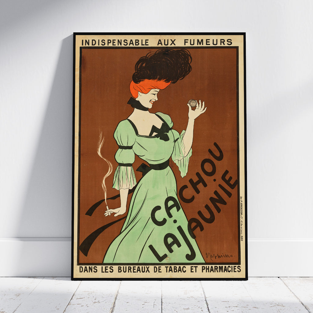 A framed vintage-style poster leaning against a white wall on a light wood floor. The poster features an illustrated woman in a light green dress holding a cigarette, with large French text reading 'Cachou Lajaunie' and additional text at the top and bottom.