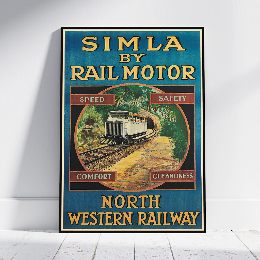 A framed vintage-style promotional poster leaning against a white wall on a light floor. The poster reads 'SIMLA BY RAIL MOTOR' and 'NORTH WESTERN RAILWAY,' with a train illustration and the words 'Speed,' 'Safety,' 'Comfort,' and 'Cleanliness.