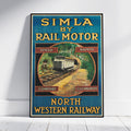 A framed vintage-style promotional poster leaning against a white wall on a light floor. The poster reads 'SIMLA BY RAIL MOTOR' and 'NORTH WESTERN RAILWAY,' with a train illustration and the words 'Speed,' 'Safety,' 'Comfort,' and 'Cleanliness.