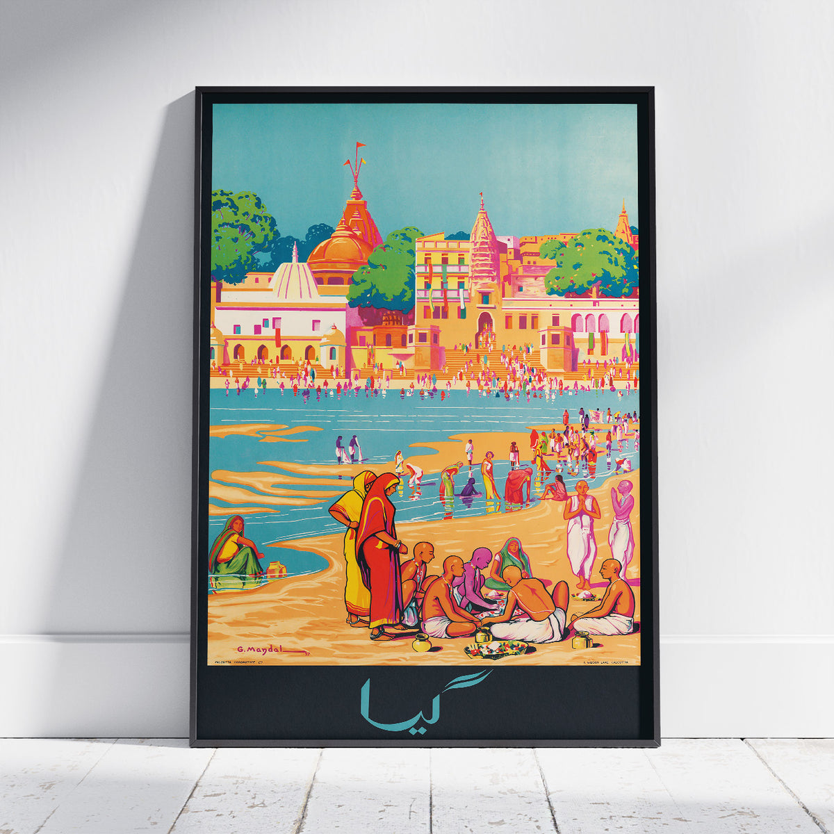 A framed art print featuring a colorful, stylized illustration of a beach and harbor scene with people, buildings, domes, and boats. The print is displayed in a black frame against a white wall on a light wood floor.