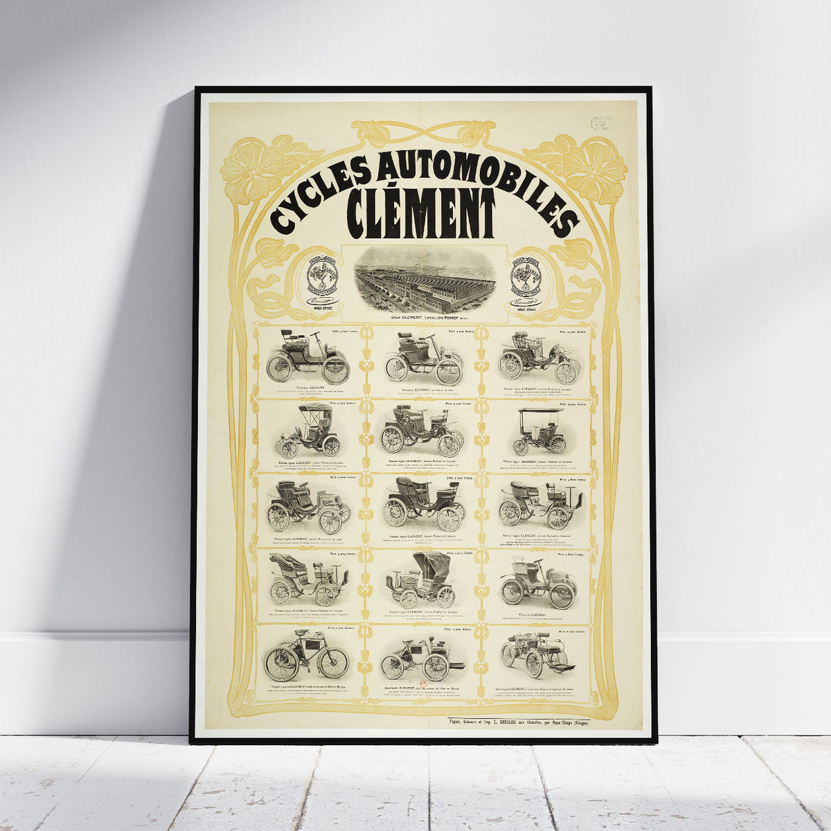 A framed vintage poster titled 'CYCLES AUTOMOBILES CLÉMENT' leaning against a white wall on a light wood floor. The poster features an aged cream background with ornate gold borders and black illustrations of early automobiles and motorcycles from multiple eras.