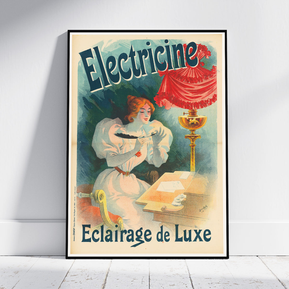 A framed vintage-style poster leaning against a white wall on a light wood floor. The poster features the French text 'Electricine' and 'Eclairage de Luxe' and depicts a woman in a white dress at a desk beside a glowing lamp with a red draped shade.